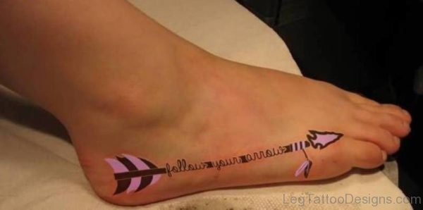 Lovely Pink Colored Arrow With Words Tattoo On Foot